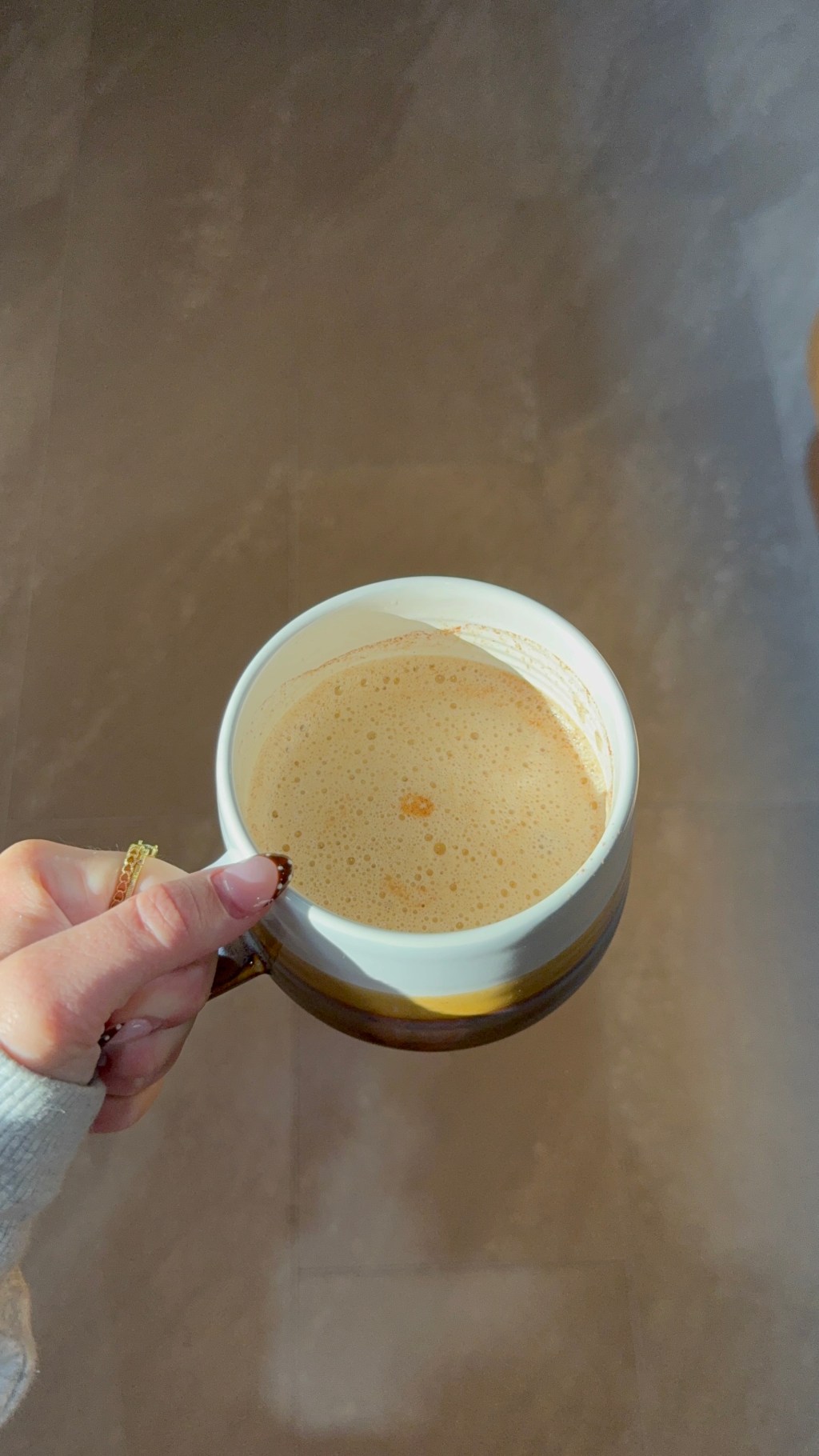 A woman's hand holding a coffee in a decorative mug
